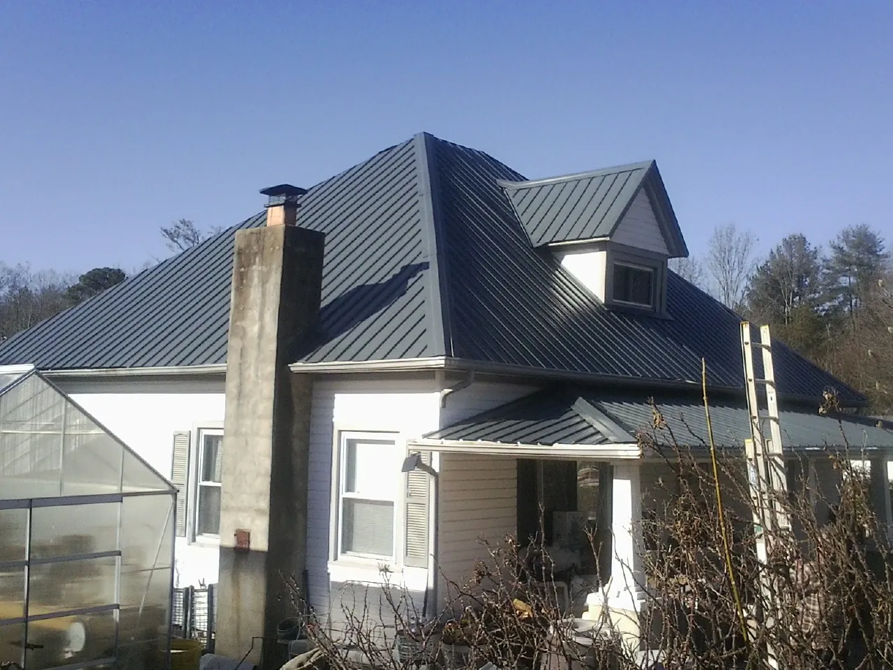 Dark blue standing seam metal roof on a white farmhouse with dormer — Slate & Tile Roof Repair by Roofing Brothers in Hercules