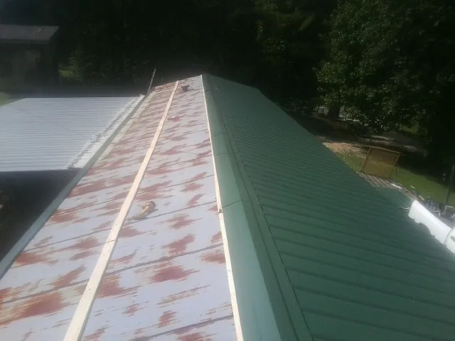 Old rusted panels beside newly installed green metal roofing — Wind Damage Roof Repair by Roofing Brothers in Hercules