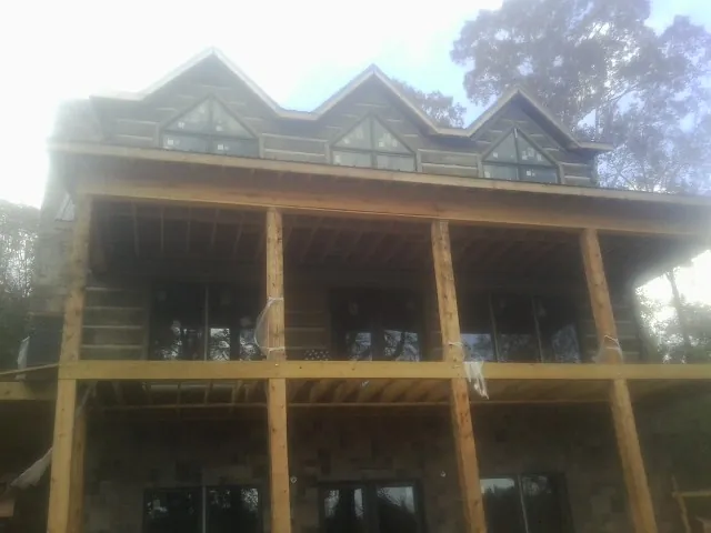 Dormers and porch framing on a large log home under construction — Roof Coating work by our crew in Hercules