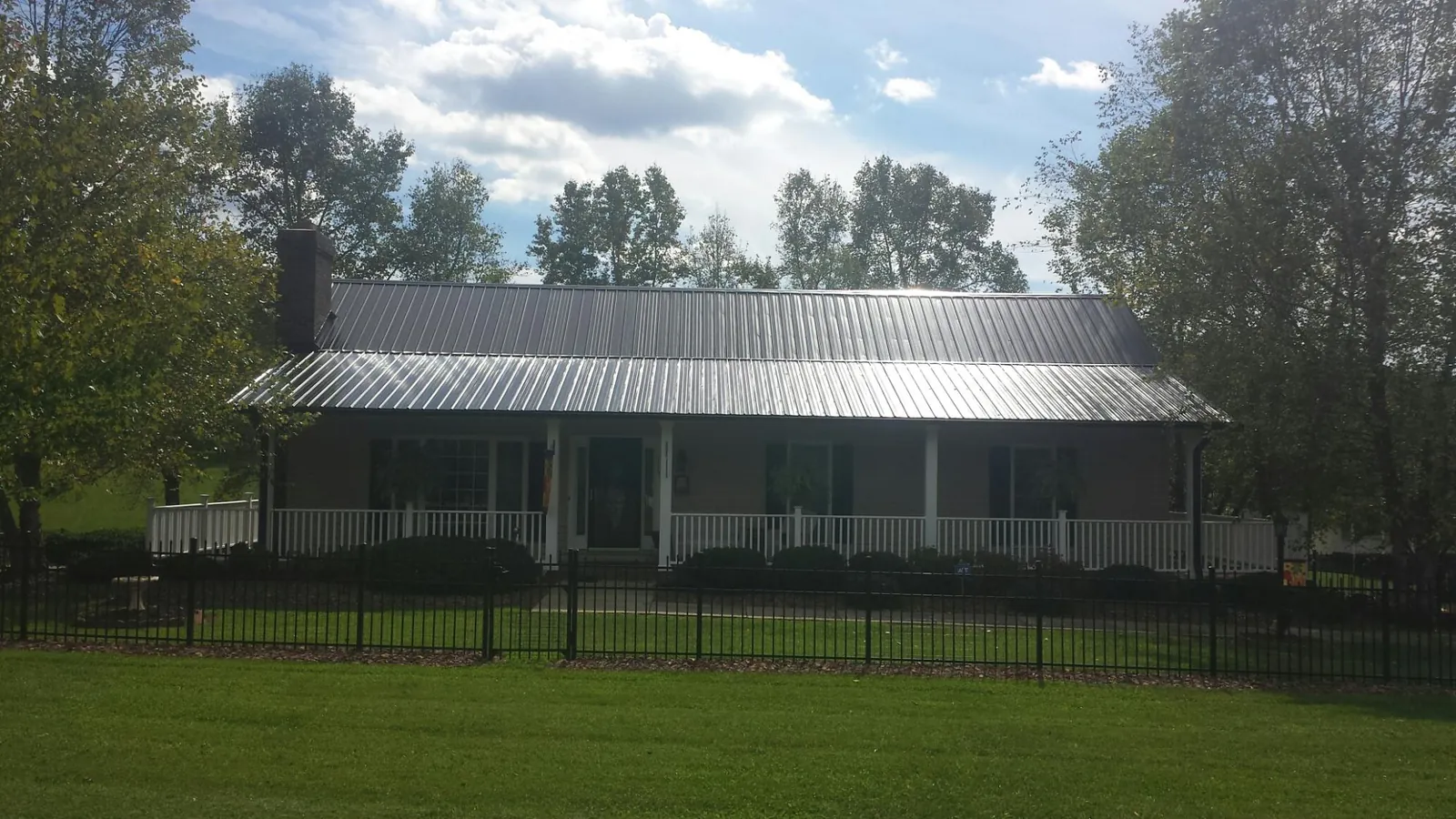 Gray metal roof on a brick ranch with a full width front porch — Gutter Guard Installation work by our crew in Hercules